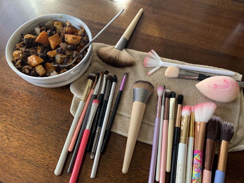 photo of a table with makeup brushes drying on a small towel and a bowl of sweet potatoes and black beans next to it