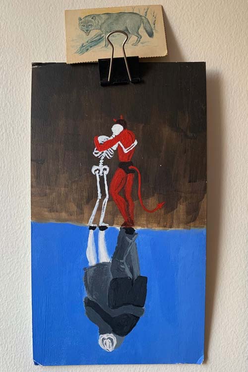 a painting where the top half is a skeleton and santan embracing each other and mirrored below them are a couple embracing each other. resting on top of the painting is the wolf card from the previous two photos