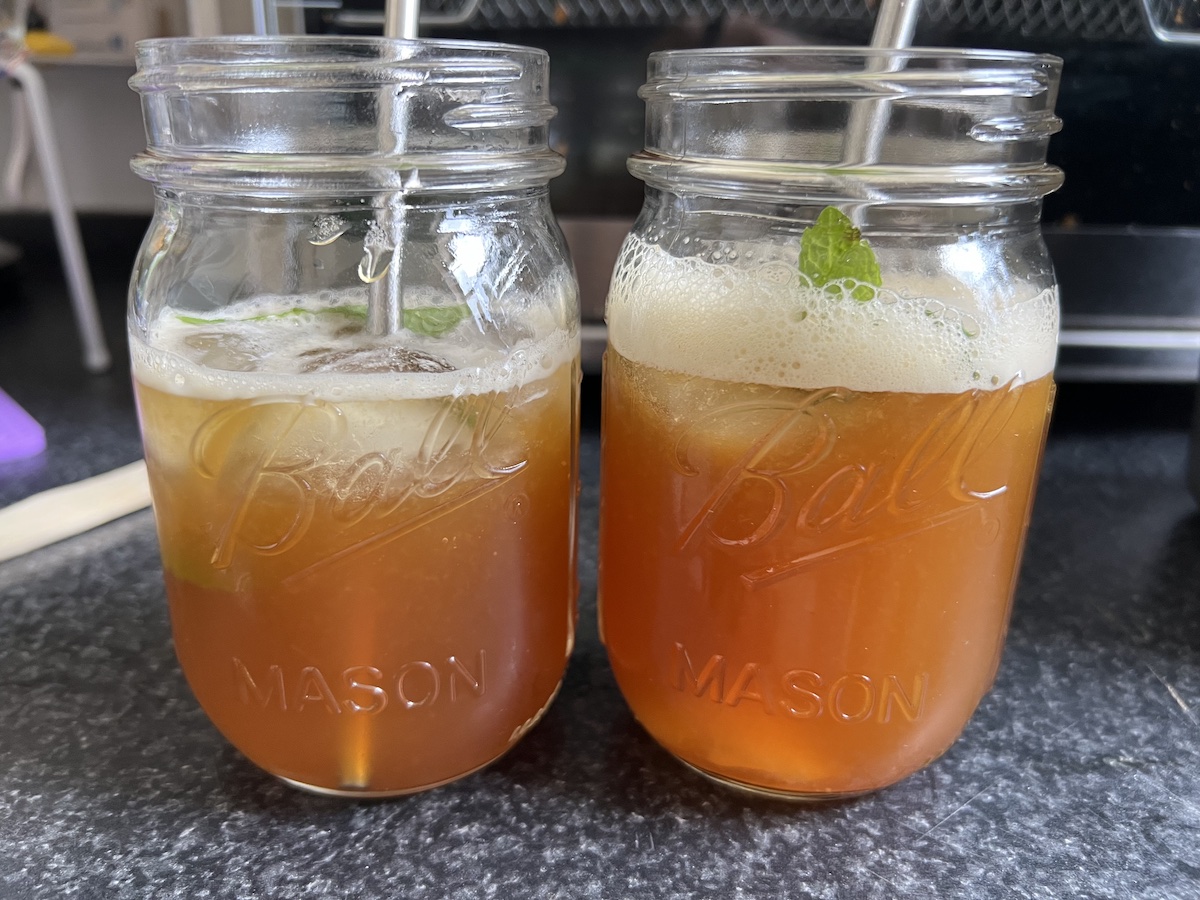 two mason jars full of fresh, cold arnold palmers with fresh mint and metal straws