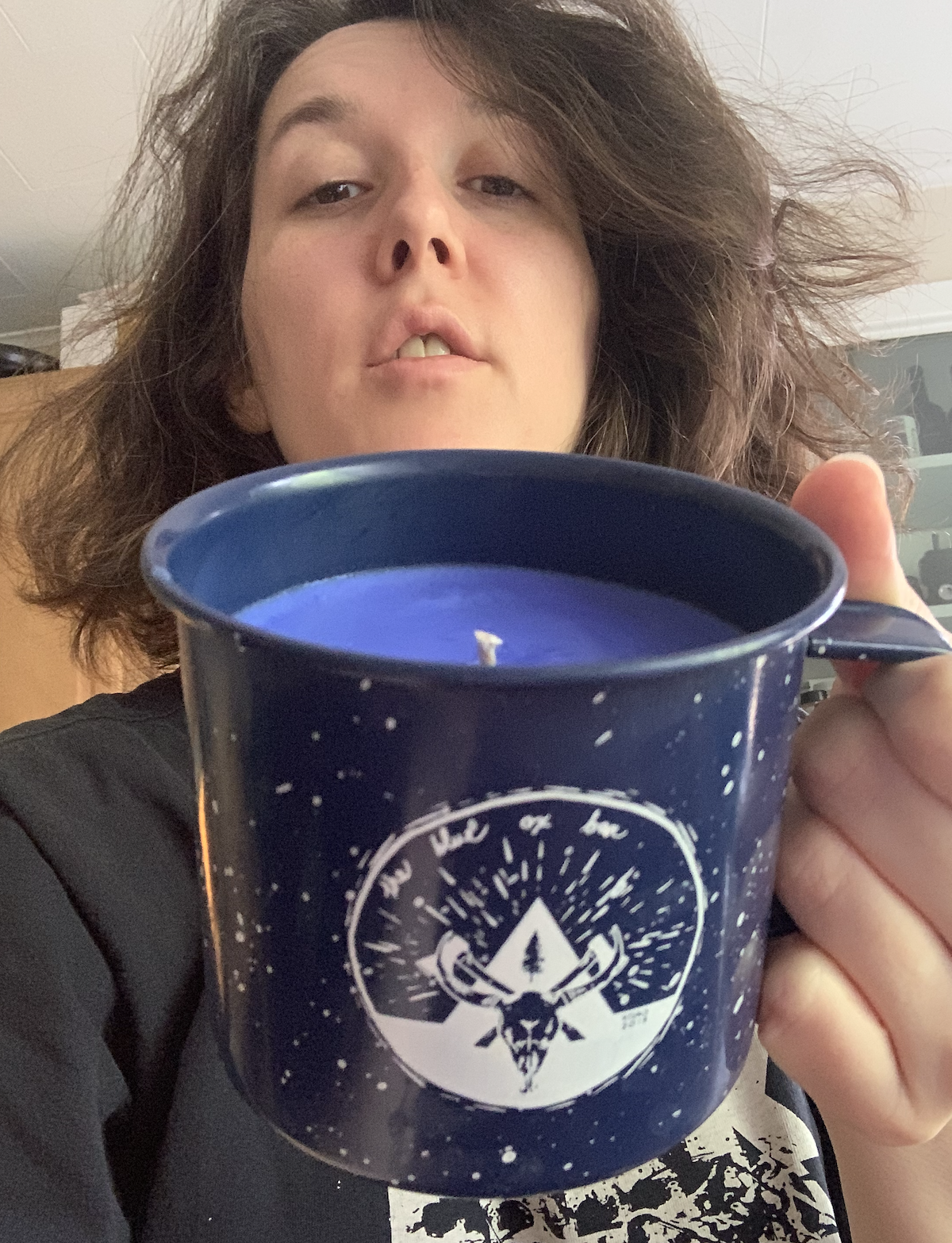 photo of me holding up my tin mug candle like it's a cup of coffee