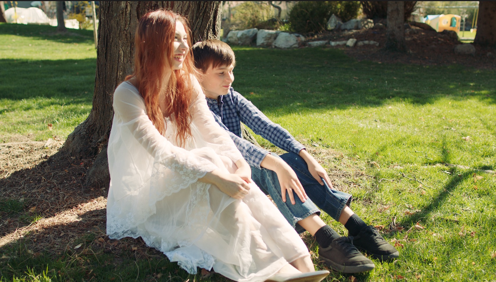 Boy and Mother sitting on grass watching the blue sky