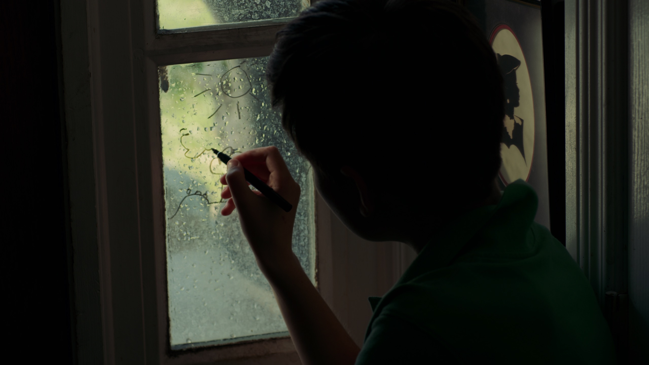 Boy drawing on the window sadly
