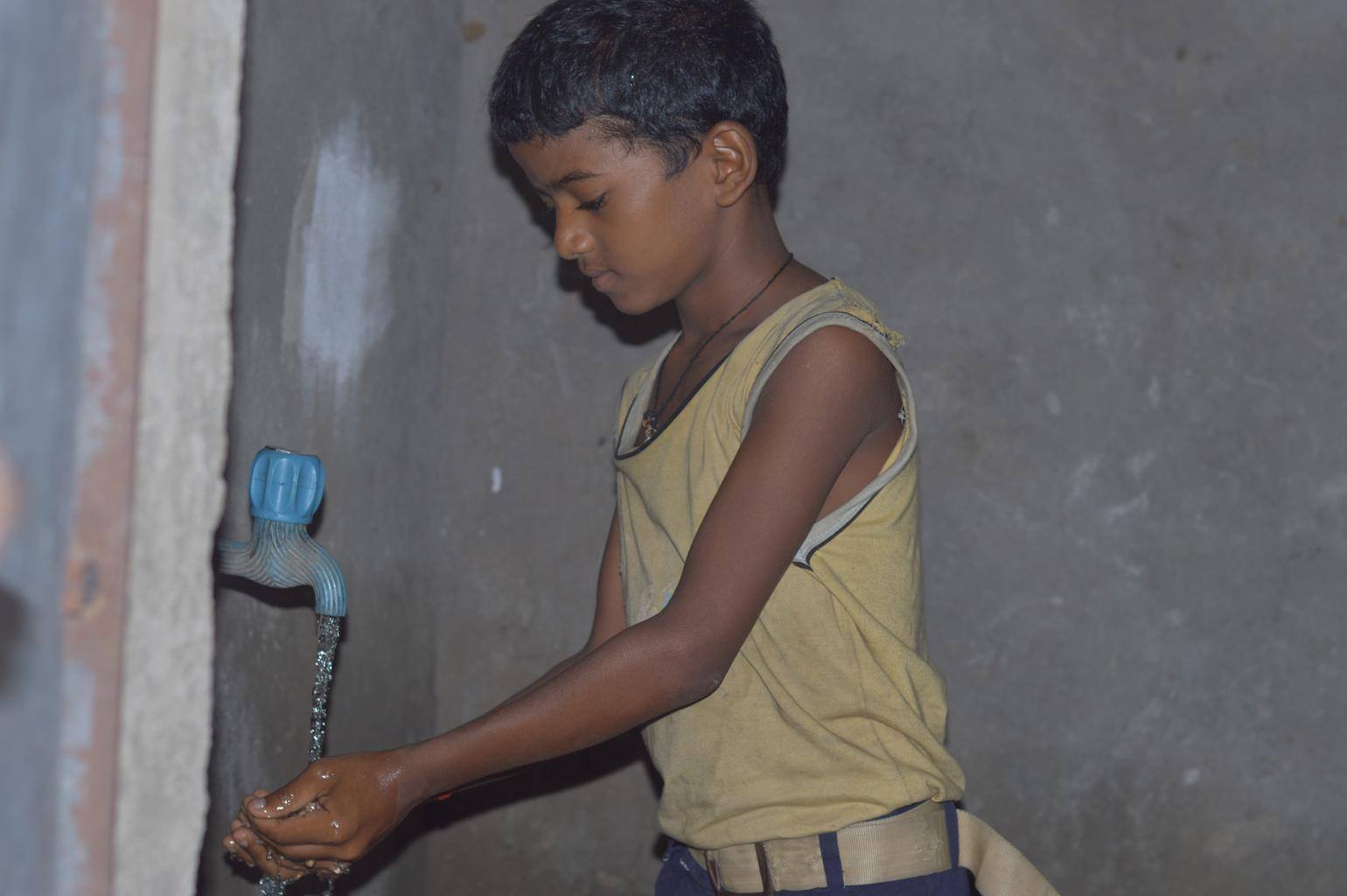 a young boy in gambhariganda getting water young boy getting water from the new well