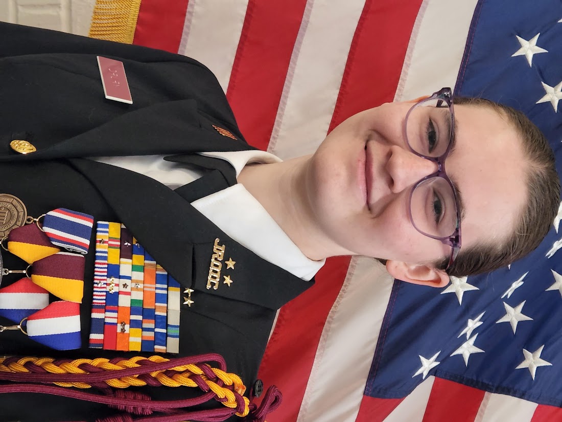 Picture of Allison Drury standing in front of the American flag with her dress blue uniform on