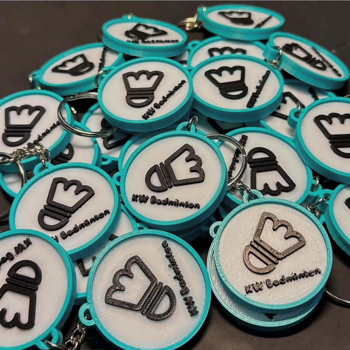 A pile of KWBadmintonc logo keyrings